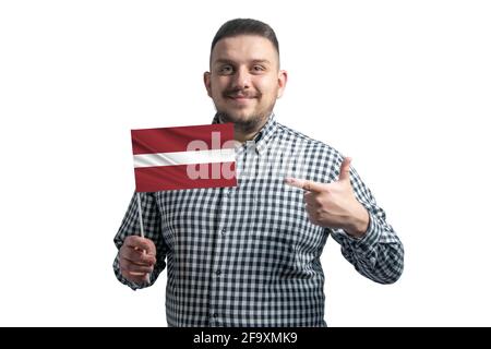 Homme blanc tenant un drapeau de la Lettonie et pointe le doigt de l'autre main sur le drapeau isolé sur un fond blanc. Banque D'Images