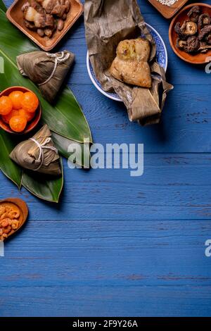 Zongzi riz boulonnage avec des ingrédients vue de dessus pour le festival chinois traditionnel de bateau-dragon (Festival Duanwu) sur fond bleu de table en bois. Banque D'Images