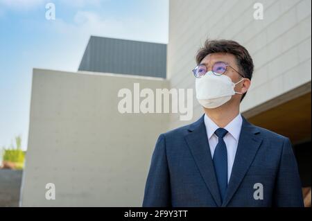 Homme d'affaires asiatique d'âge moyen dans la ville portant un masque facial. Banque D'Images