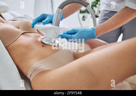 Belle femme élégante en peignoir blanc avec le corps parfait obtenir traitement anti-graisse dans le salon de beauté Banque D'Images