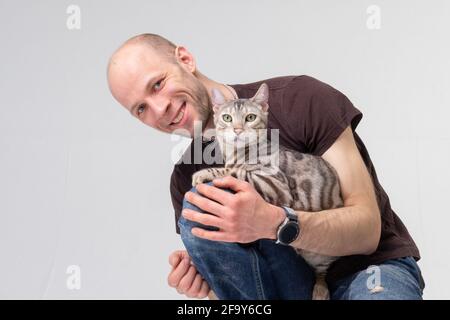 Homme positif tenant un gros chat bengale. Gros plan portrait en studio Banque D'Images