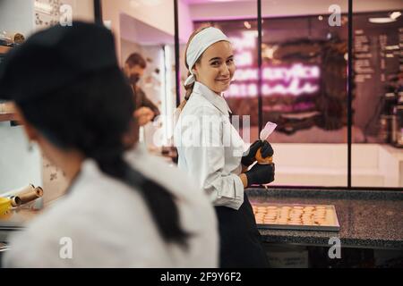 Chef sympathique posant avec une seringue pleine de glaçage Banque D'Images