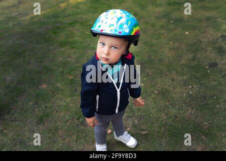 Mignon petit adorable caucasien heureux tout-petit dans le casque de sécurité demander à regarder aller avoir plaisir à cheval de kick scooter, voyage à vélo dans le siège d'enfant de vélo Banque D'Images