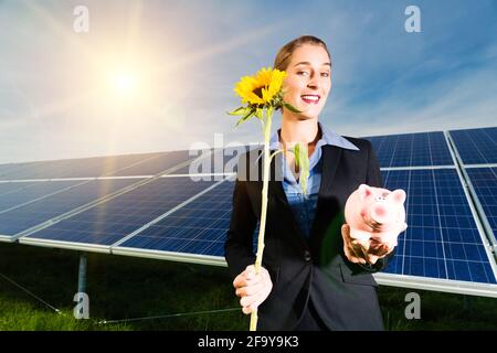 Système photovoltaïque avec panneaux solaires pour la production d'énergie renouvelable par l'énergie solaire, l'investisseur est en face d'une porcgybank et d'un soleil Banque D'Images