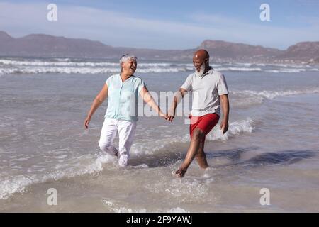 Heureux couple afro-américain senior tenant les mains et s'amusant sur la plage Banque D'Images