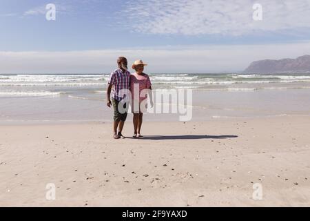 Heureux couple afro-américain senior marchant ensemble sur la plage Banque D'Images