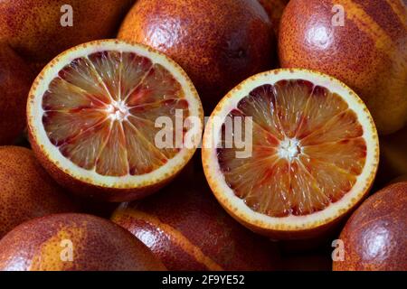 Les oranges de sang entières et coupées en deux se rapprochent du cadre entier un arrière-plan Banque D'Images