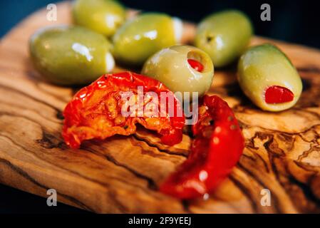 gros plan d'une planche à découper en bois de bambou avec le soleil tomates séchées et olives Banque D'Images