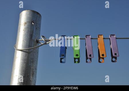 Vue avant des pinces en tissu coloré accrochées au fil avec ciel bleu en arrière-plan Banque D'Images