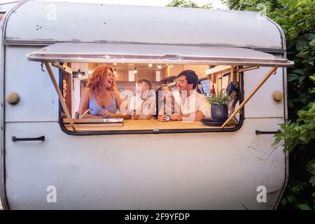 Une famille de voyageurs gaie regarde de la maison mobile, de la caravane. Les gens s'amusent, le père-mère sourit aux enfants. Frère sœur FO Banque D'Images