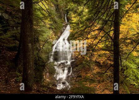 Une vue de Moss Glen Falls, une chute d'eau dans le Vermont, États-Unis, prise d'une distance à travers les arbres en automne / automne Banque D'Images