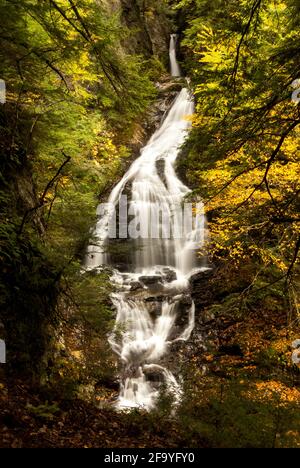 Une vue de Moss Glen Falls, une chute d'eau dans le Vermont, États-Unis, prise d'une distance à travers les arbres en automne / automne Banque D'Images