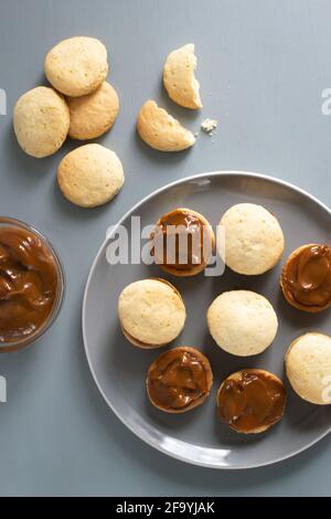Biscuits Alfahores sur une assiette grise sur fond gris avec du lait condensé dans un bol en verre. Biscuits maison traditionnels. Concept de cuisine maison. Hori Banque D'Images
