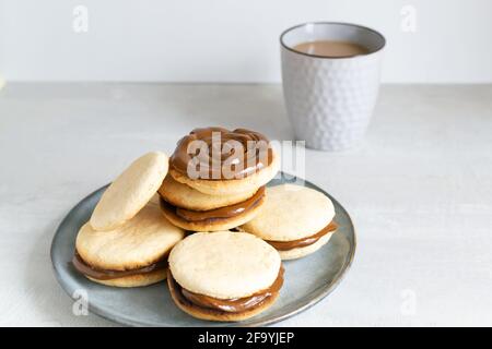Biscuits Alfahores au lait condensé sur une assiette grise avec une tasse de café. Biscuits maison traditionnels. Concept de cuisine maison. Orientati horizontal Banque D'Images