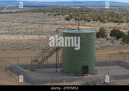 Réservoir de stockage d'essence de pétrole brut extrait avec escaliers et barrière de gravier stockant le combustible fossile pour raffinage après transfert à l'usine de production. Banque D'Images