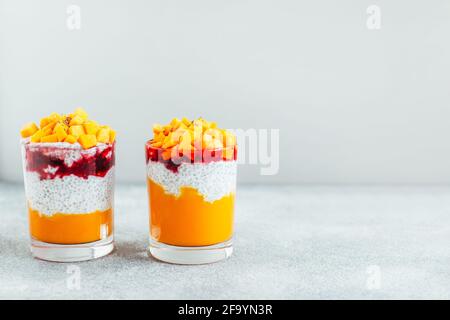 gros plan de deux verres avec purée de courge de chia et de citrouille confiture de fraises sur fond gris Banque D'Images