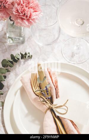 Vue en hauteur sur la table avec couverts dorés décorés de branches d'eucalyptus et d'œillets. Banque D'Images