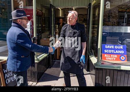 Hawick, Écosse, Royaume-Uni. 21 avril 2021. George Galloway , fondateur du parti All for Unity qui fait aujourd'hui campagne dans les rues de Hawick contre une frontière difficile avec l'Angleterre. Il rencontre Robbie Hayes propriétaire de la boutique de baguettes de Hawick qui a une affiche All for Unity dans sa fenêtre. Iain Masterton/Alay Live News Banque D'Images