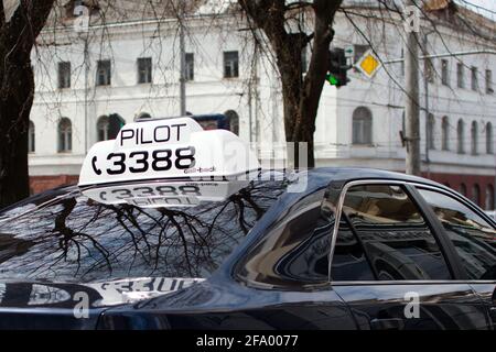 Visionneuse blanche du pilote de service de taxi sur le toit du passager voiture sur fond flou de la rue de la ville Banque D'Images