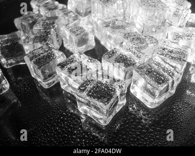 cubes de glace artificiels sur noir pulvérisé avec de l'eau Banque D'Images