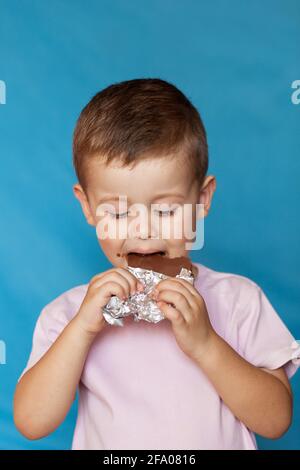 Joyeux garçon avec une barre de chocolat. Bar à chocolat mignon petit garçon. Très mignon enfant avec chocolat, isolé. Banque D'Images