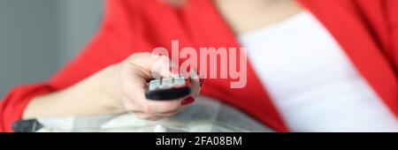 Femme allongé sur des coussins de canapé et tenant la télécommande de la TV contrôle dans ses mains de près Banque D'Images