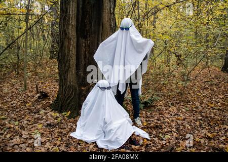 Défi fantôme dans la forêt ou le parc. Deux personnes méconnaissables adolescents déguisés en fantômes avec des draps blancs et des lunettes de soleil. L'un se trouve à ano Banque D'Images
