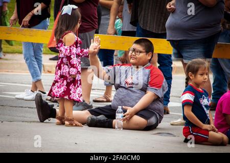 8-31-2019 Tahlequah OK Plump garçon amérindien assis haut fives petite fille en robe par la barrière dans l'observation de la foule parade Banque D'Images