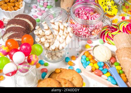 Sélection de bonbons colorés. Assortiment de bonbons, chocolats, beignets, biscuits, sucettes, vue de dessus de crème glacée sur fond blanc Banque D'Images
