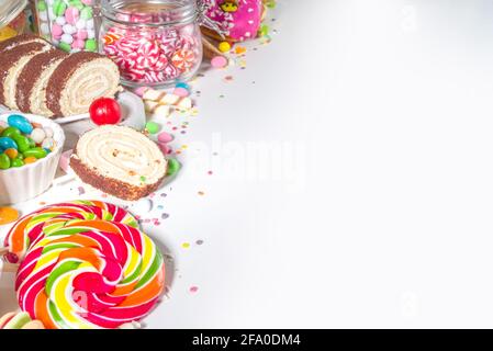 Sélection de bonbons colorés. Assortiment de bonbons, chocolats, beignets, biscuits, sucettes, vue de dessus de crème glacée sur fond blanc Banque D'Images