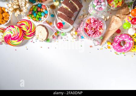 Sélection de bonbons colorés. Assortiment de bonbons, chocolats, beignets, biscuits, sucettes, vue de dessus de crème glacée sur fond blanc Banque D'Images