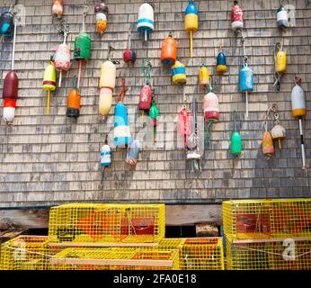 Bouées traditionnelles de homard d'époque accrochées sur le mur d'un bâtiment avec des pots de homard jaune sur le sol à Portland Maine USA. Banque D'Images