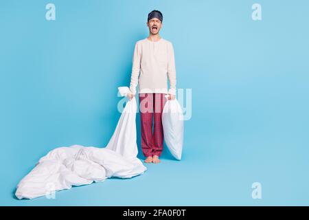 Photo portrait vue du corps entier de crier gars tenant couverture d'oreiller isolée sur fond bleu vif Banque D'Images