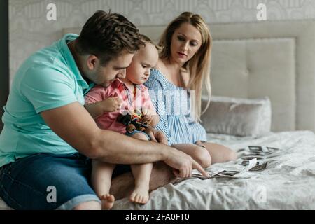 Portrait d'une famille qui regarde des images échographiques de son bébé. Une femme enceinte avec son partenaire préparant son enfant pour un nouveau frère ou une sœur. Banque D'Images