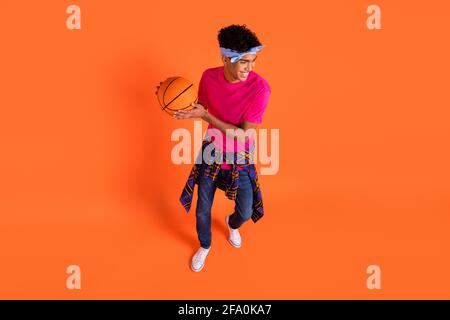 Photo grand angle jeune homme dans des vêtements élégants jouant le basket-ball rigole isolé sur fond orange vif Banque D'Images