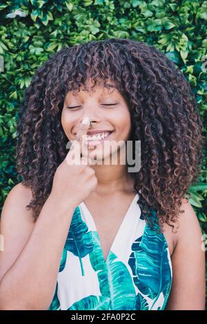 Portrait d'une femme africaine souriant et touchant son nez Banque D'Images