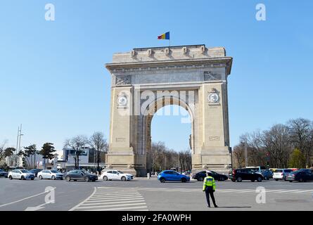 BUCAREST, ROUMANIE - 11 AVRIL 2021 : un policier dirige la circulation à l'arc triomphal du pays, construit pour la première fois après l'indépendance de la Roumanie en 1878 Banque D'Images