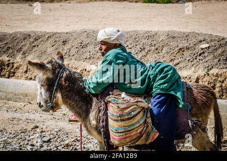 Midelt, Maroc - 11 avril 2015. Un vieil homme handicapé qui se déplace sur l'âne et supplie pour de l'argent Banque D'Images