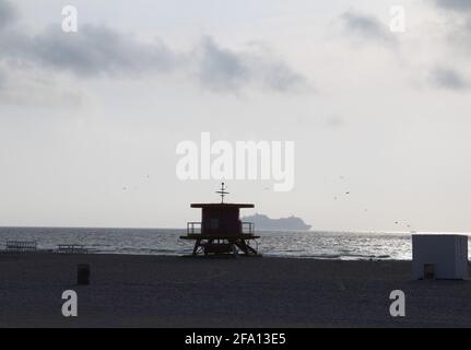 Horizon au lever du soleil à South Beach, dans la ville de Miami Beach, en Floride, avec tour de maître-nageur et silhouette d'un bateau de croisière en arrière-plan. Crise du tourisme Banque D'Images