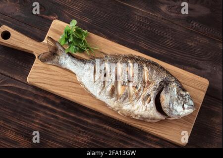 Poisson dorada grillé sur la planche de bois Banque D'Images