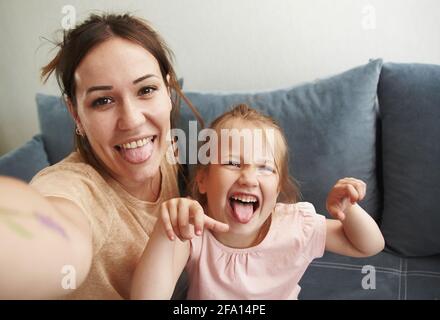 Une jeune mère avec sa petite fille prend des selfies et idiot autour de regarder l'appareil photo. Banque D'Images