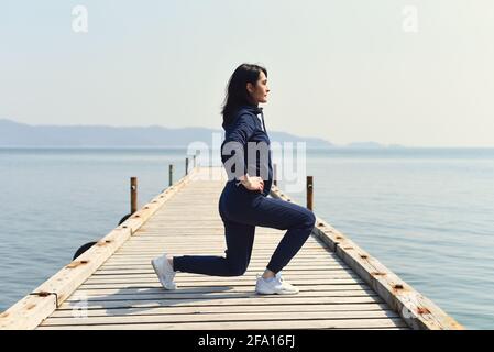 45 ans Femme russe qui s'accroupisse sur une jetée en bois au bord de la mer japonaise Banque D'Images