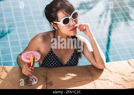 Jeune femme en bikini piscine boisson jus de fruit cocktail, vacances été concept de vacances Banque D'Images