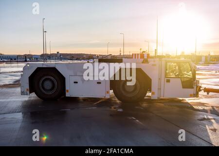 L'avion tracte le tracteur au niveau du tablier de l'aéroport dans la lumière du soleil du soir Banque D'Images