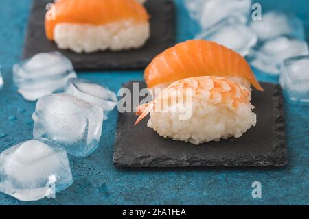 Gros plan des sushis Nigiri sur l'ardoise avec des glaçons arrière-plan bleu Banque D'Images