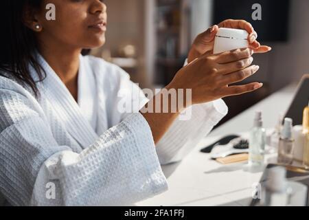 Charmante jeune femme tenant un pot de crème cosmétique Banque D'Images