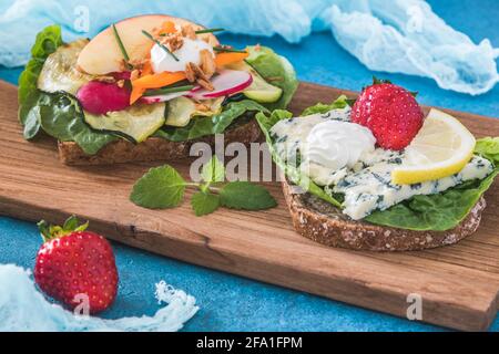 Deux sandwichs ouverts danois vegeterain avec courgettes grillées et bleu fromage sur bois et fond bleu frais Banque D'Images