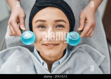 Jeune femme patiente massée avec des globes de glace du visage Banque D'Images