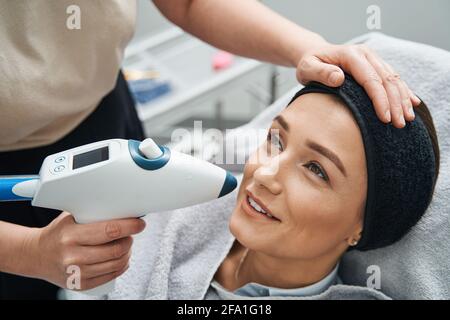 Client satisfait qui subit une procédure de rajeunissement du visage Banque D'Images