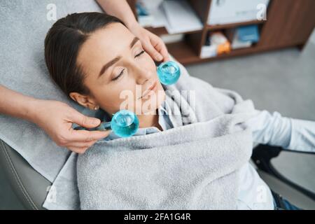 Patient allongé avec ses yeux fermés pendant la procédure de serrage de la peau Banque D'Images